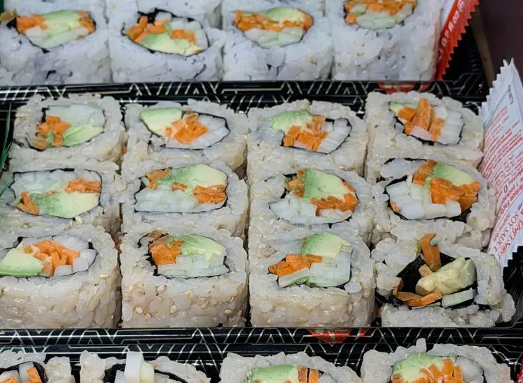 Hand-rolled sushi pieces with avocado and orange filling arranged in a display case at Hashi Sushi